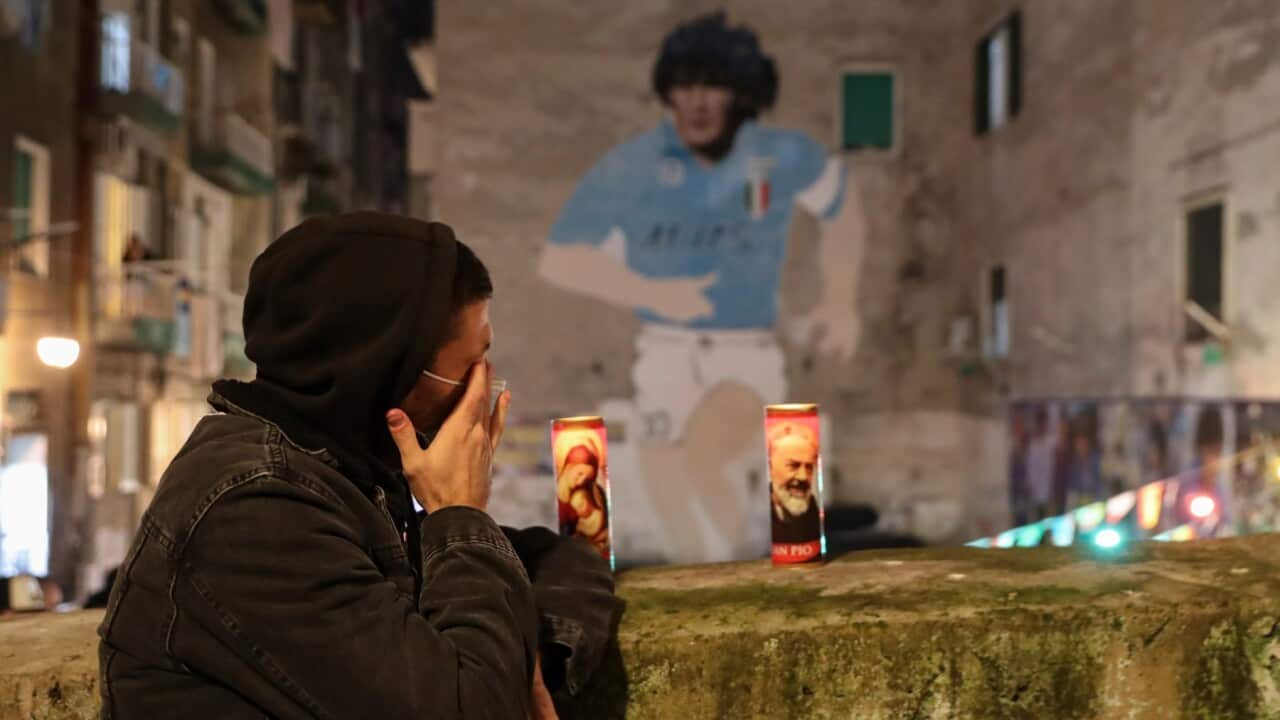 A man cries under a mural depicting soccer legend Diego Maradona, in Naples, Italy, Wednesday, Nov. 25, 2020.