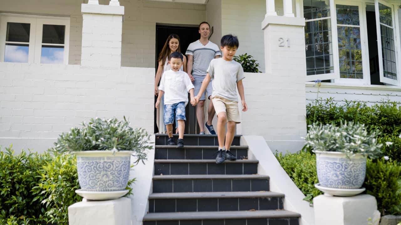 A young family with two small children walks down the stairs of a house