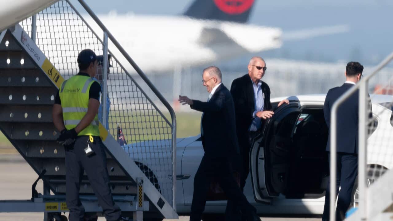 A man boards a plane via steps after stepping out a car. Another man holds the car door open for him, while another man in a high vis vest looks on.