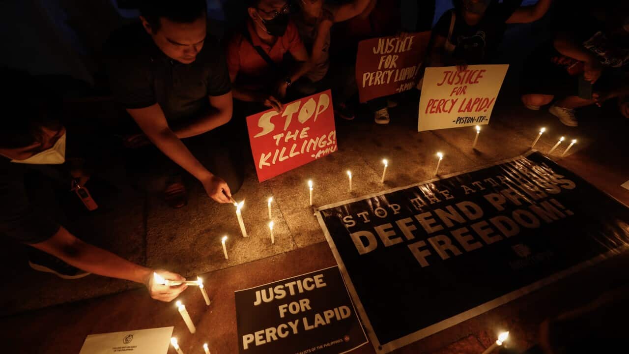 Protesters in Manila place lit candles around signs during a rally against the killings of media personalities