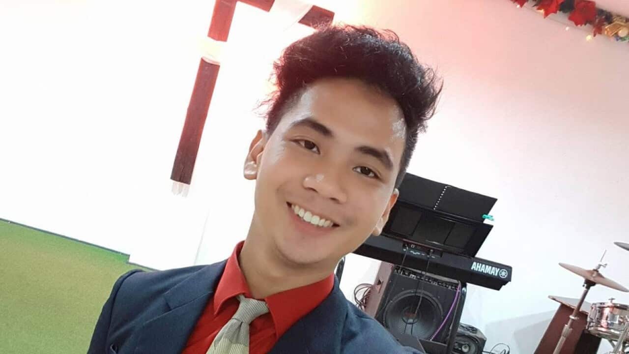 A young man in a suit and tie smiles as he takes a selfie