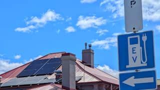 EV charging station road sign with solar panels in background.