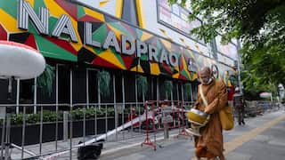 A monk walks past a fenced of pub in Thailand