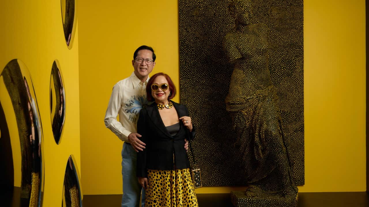 Lito and Kim Camacho standing in front of Yayoi Kusama's Statue of Venus Obliterated by Infinity Nets 2/10, 1998 on display as part of the Yayoi Kusama exhibition at NGV International, Melbourne until 21 April 2025. Collection of Lito and Kim Camacho © YAYOI KUSAMA.