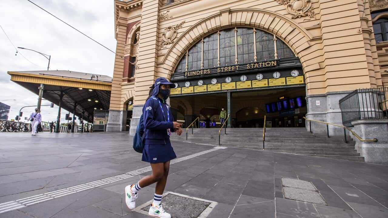 An Australian Open ballgirl walks past the Flinders Street Station on 14 February, 2021 in Melbourne.