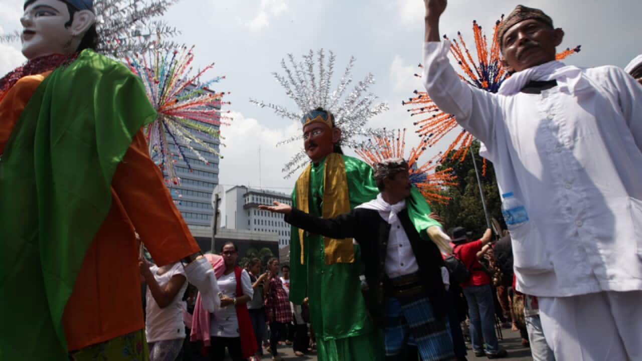 Indonesians dance among giant-sized puppets