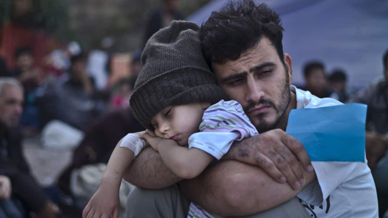 A Syrian refugee child sleeps on his father's arms