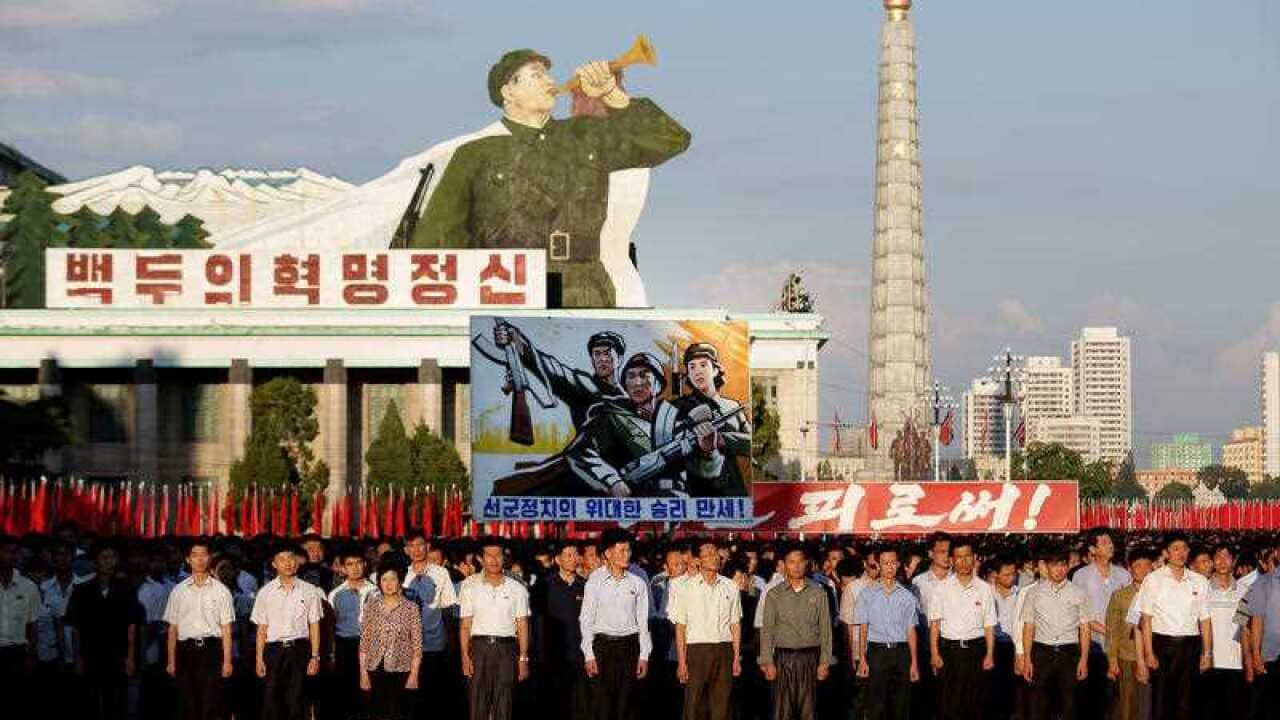Men and women pump their fists in the air and chant "Defend!" as they carry propaganda slogans during an anti-U.S. rally attended by thousands of North Koreans to mark the 66th anniversary of the start of the Korean War