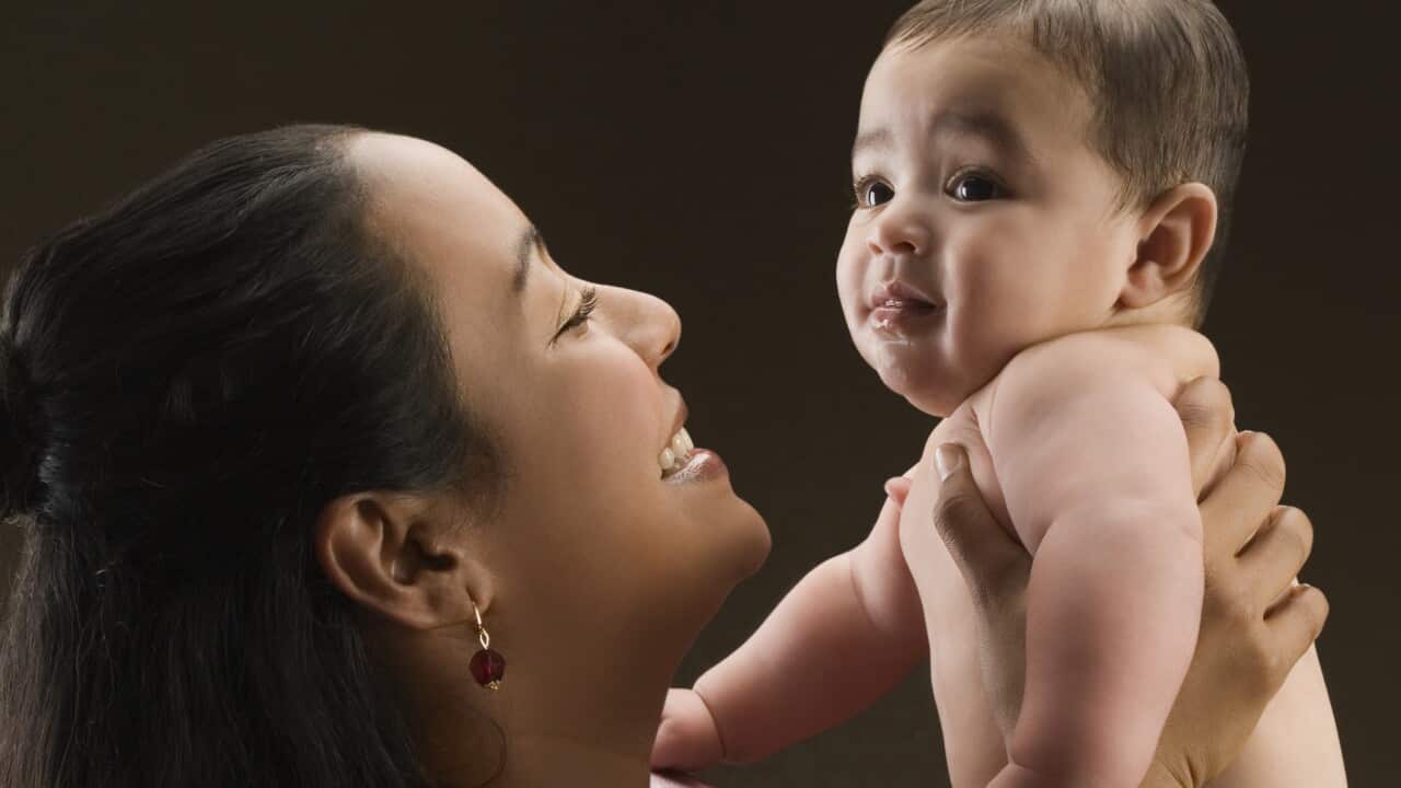 Close-up of a young woman carrying her son and smiling