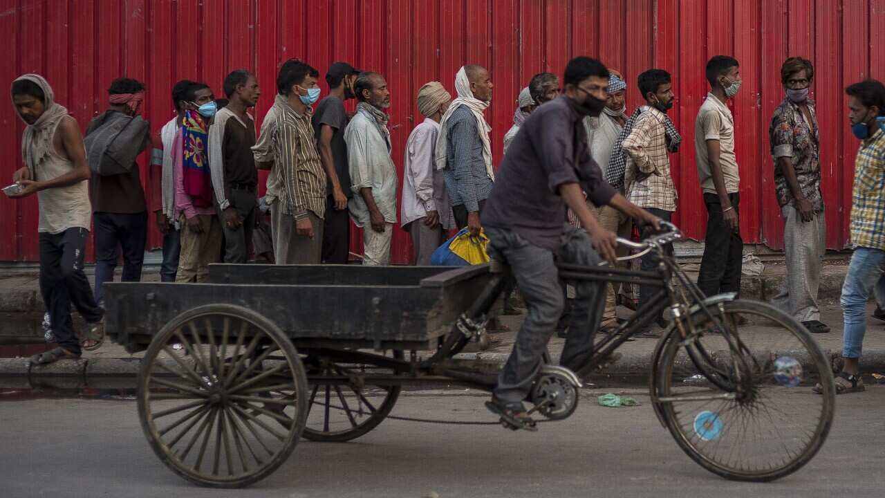 Rickshaw-pullers and other migrant laborers queue up to receive food distributed by a charity amid lockdown in New Delhi.