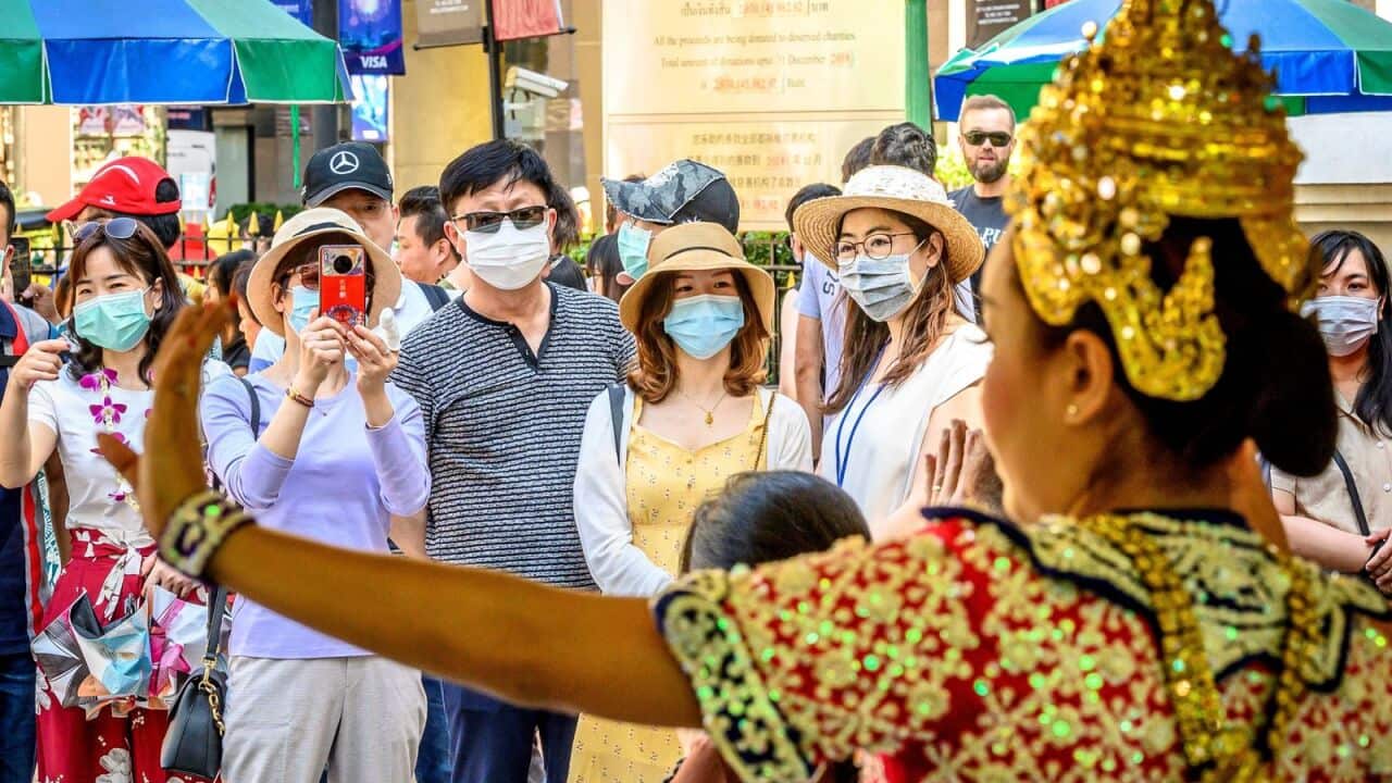 Chinese tourists with face masks watch a traditional Thai dance at Erawan shrine, a popular spritual landmark in Bangkok on January 27, 2020.