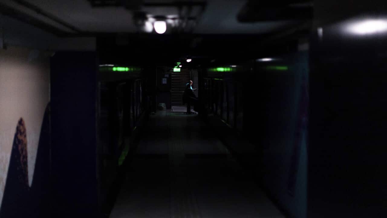A subway employee stands in the hallways of Buenos Aires's subway lit only by emergency lights during the blackout