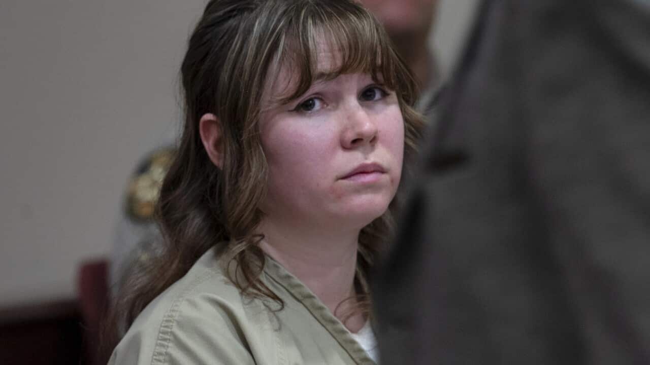 A woman with long hair staring into the distance looking sad while sitting down