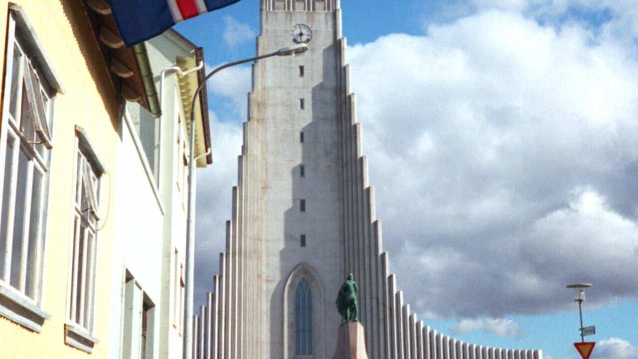 The Icelandic flag flies near Hallgrimskirkja Lutheran Cathedral, background, in Reykjavik, Iceland