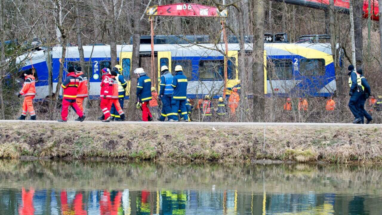Task force units watch a crane lift a train car