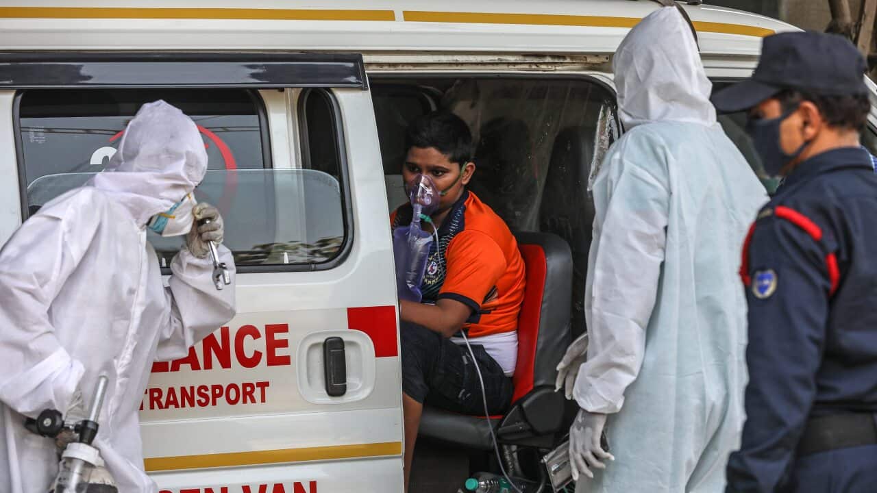 Health workers attend to a suspected COVID-19 patient waiting outsidee a health centre in Mumbai, India, 19 April 2021.