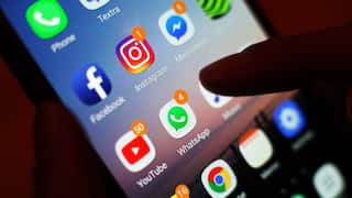 A finger taps a smartphone screen filled with social media app icons.