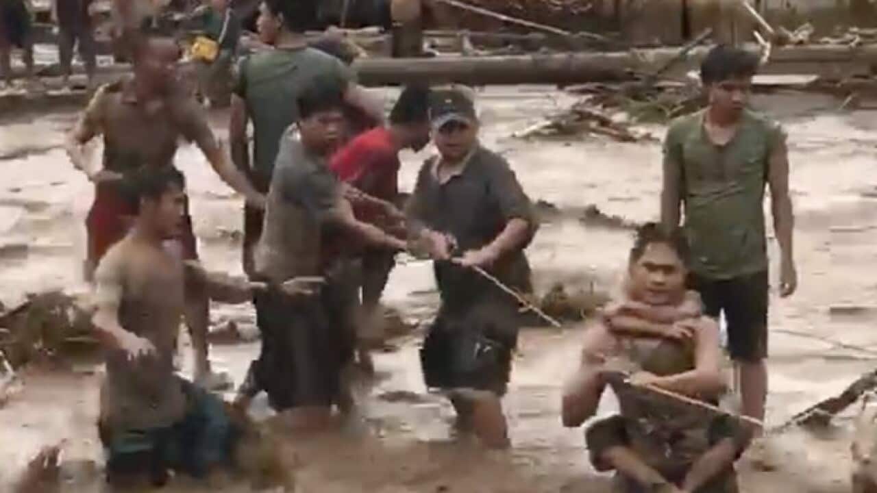 villagers carry cross raging flood waters in Lanao del Norte, Zamboanga Pennisula, southern Philippines
