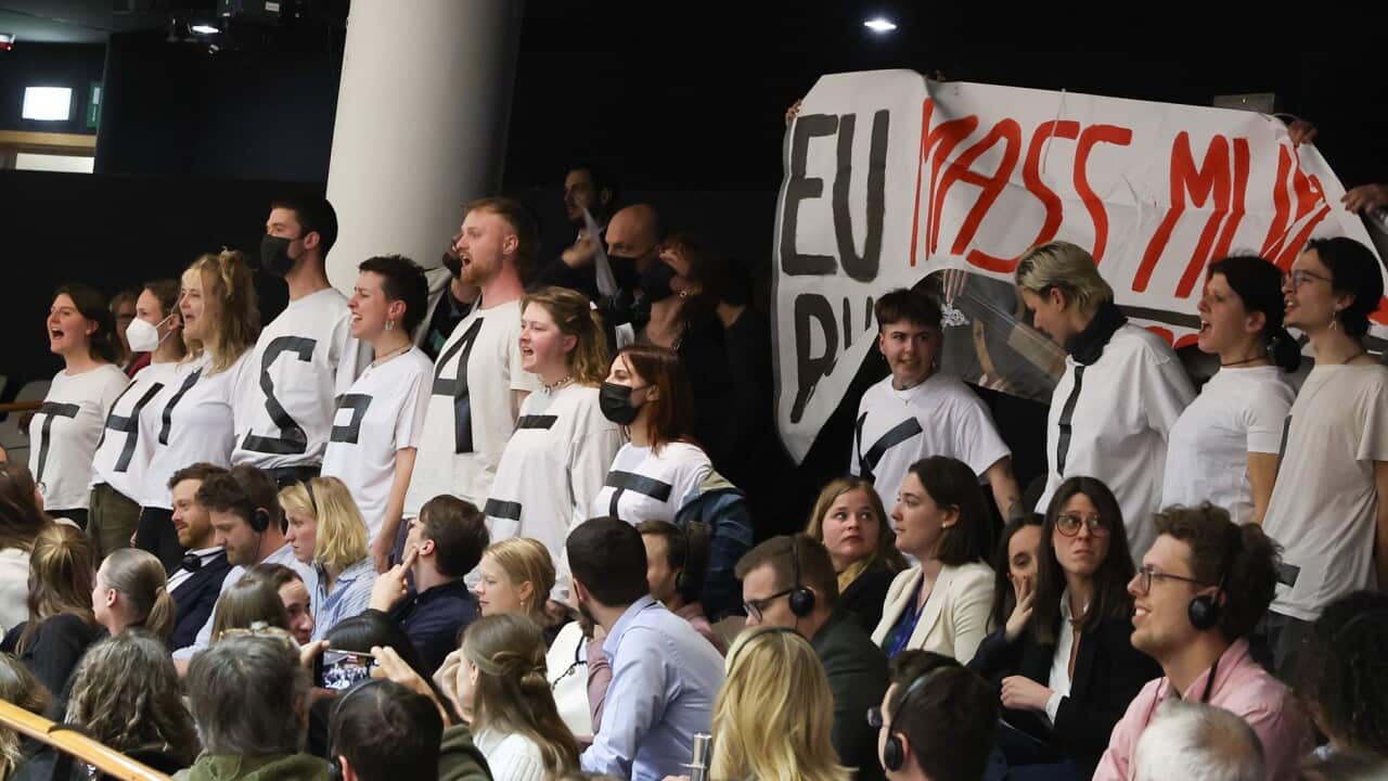 Activists protest with a placard reading 'EU mass murder' against the Migration and Asylum package (AAP)