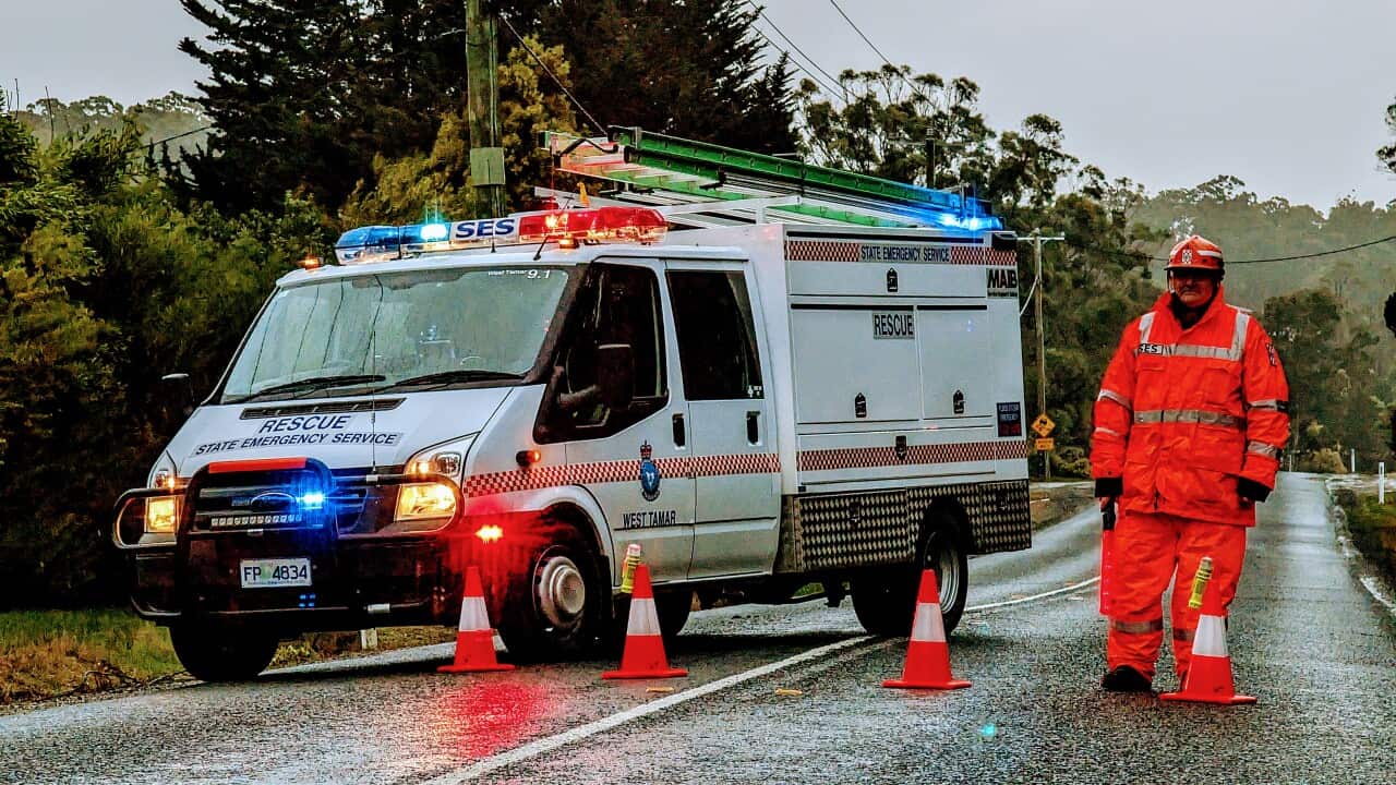 An emergency worker and vehicle standing on a road. There are traffic cones in between them.