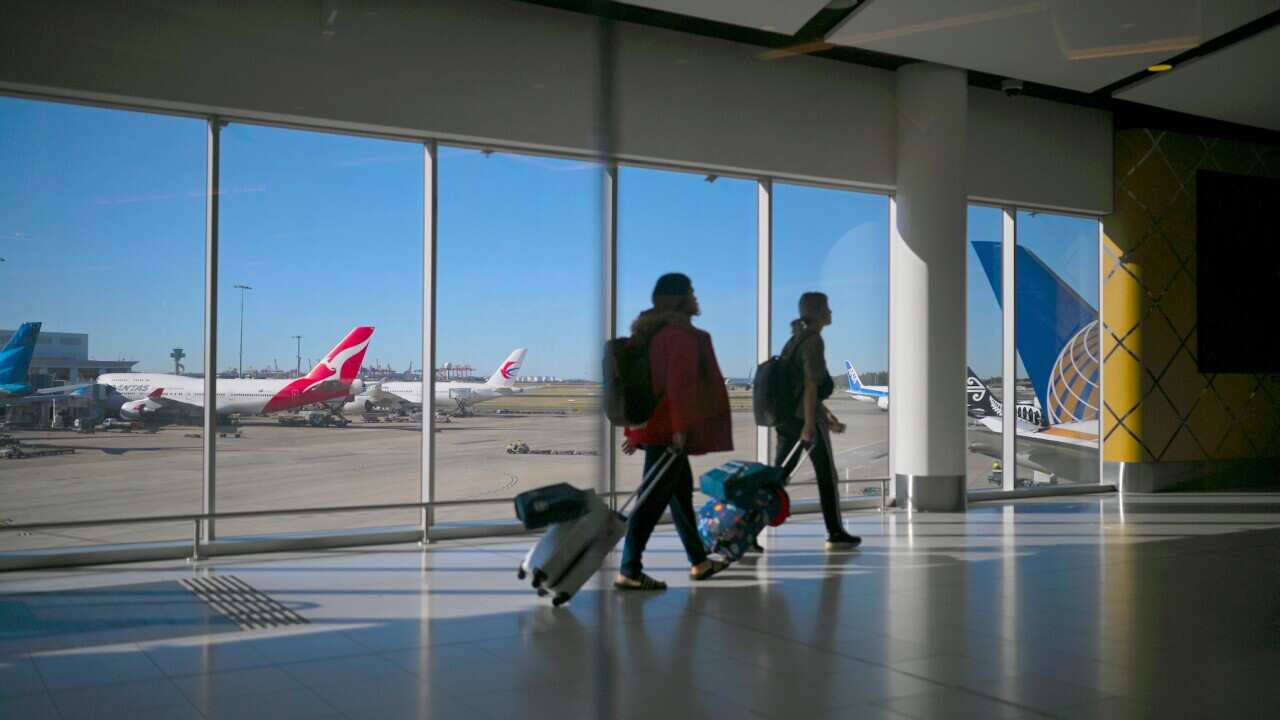 A Qantas plane is seen as passengers walk to their flights at Sydney International Airport in Sydney, Wednesday, August 21, 2019. (AAP Image/Lukas Coch) NO ARCHIVING