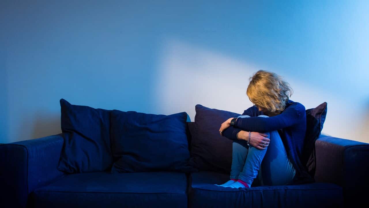 A woman sitting on a couch looking lonely
