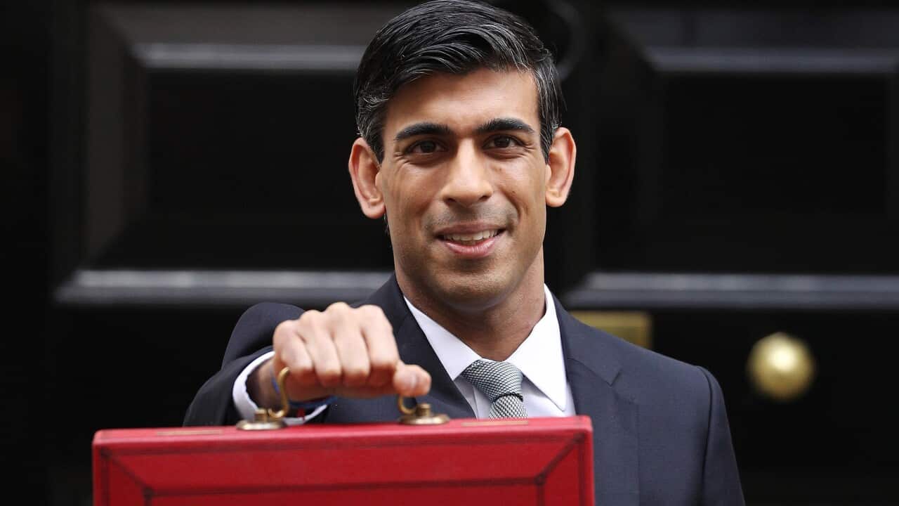 A man in a suit holds forward a briefcase.