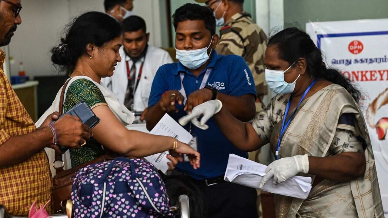 Two people examine a woman's hands at an airport to check for infections.