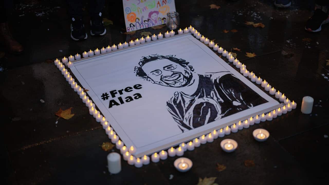 An image of a smiling man with the hashtag #FreeAlaa rurrounded by candles.