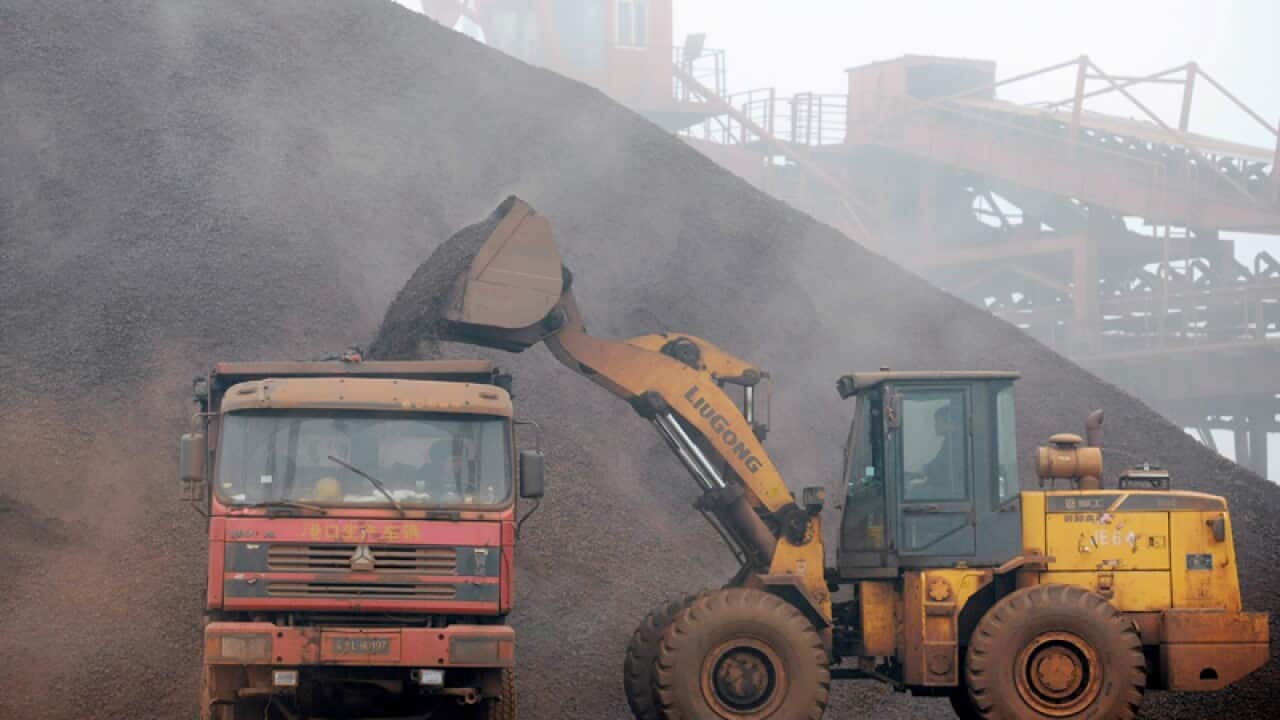 A wheel loader loads a truck with iron ore at the Port of Rizhao