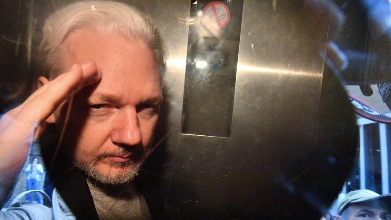 WikiLeaks founder Julian Assange gestures from the window of a prison van.