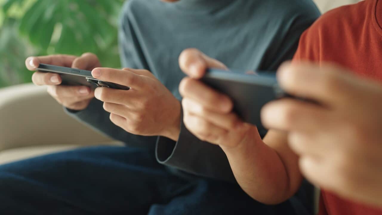 Mature and teenager playing game on smartphone at home.