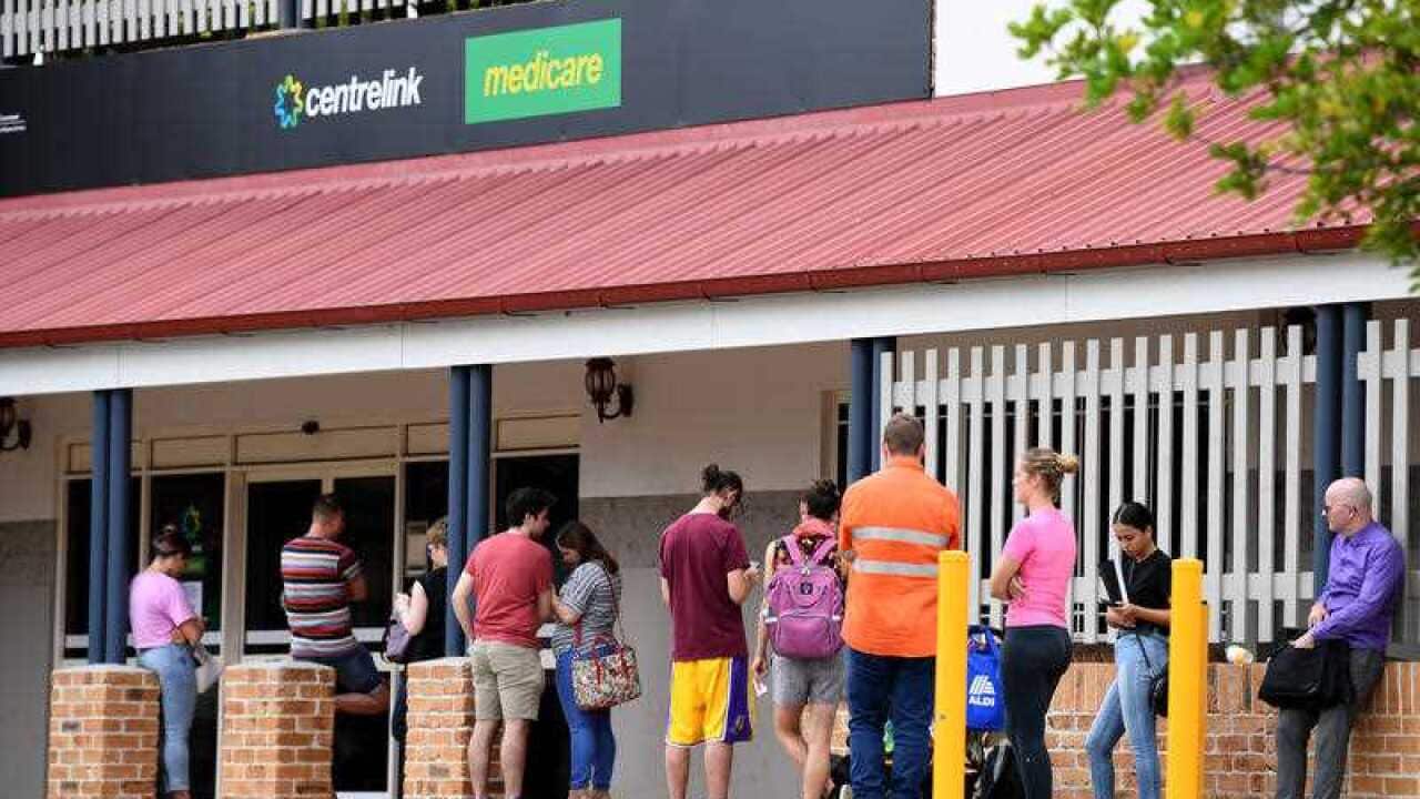 People are seen in a long queue outside a Centrelink office in Brisbane, Tuesday, March 24, 2020.
