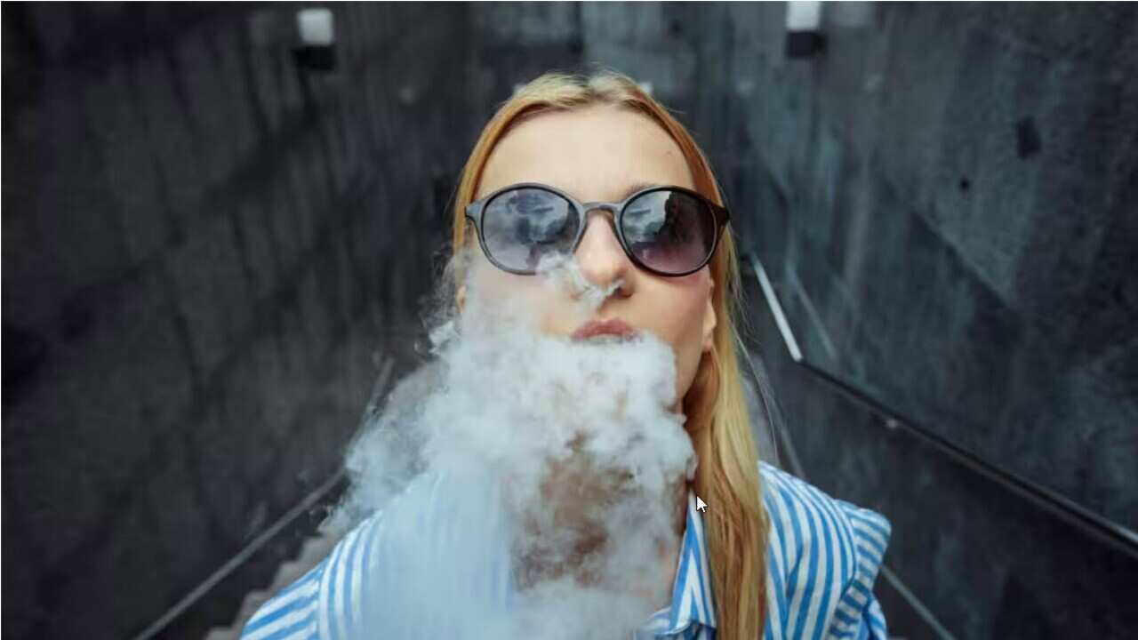 A girl vapes with smoke around her.jpg