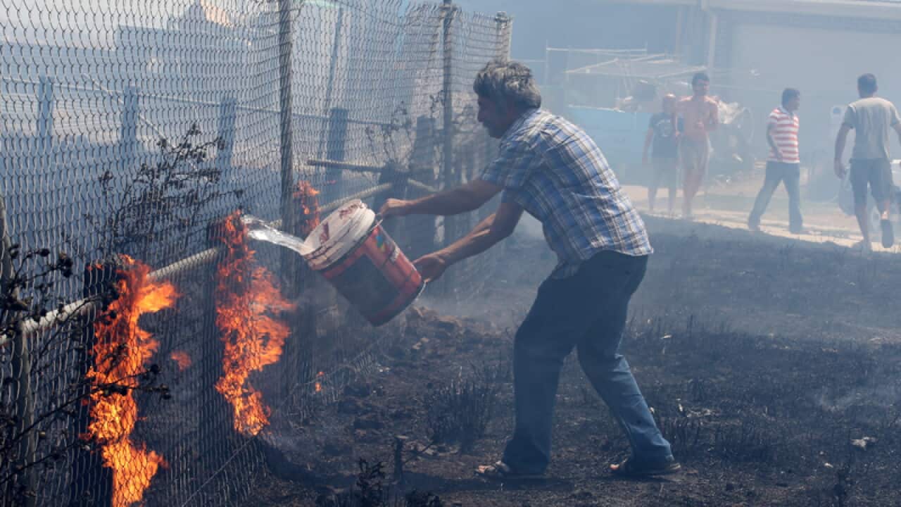 Residents with buckets battle a fast moving grass fire in Victoria