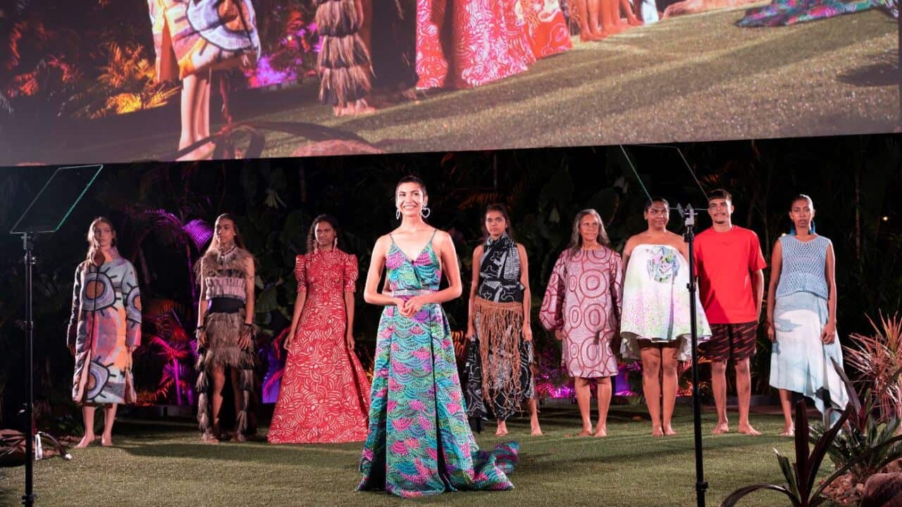 A group of people stand behind a woman onstage