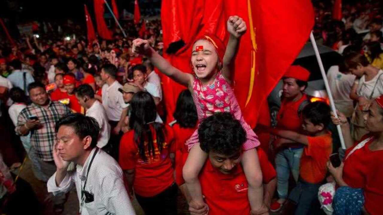A child joins adult supporters of Myanmar's National League for Democracy party to celebrate as unofficial election results are posted outside the NLD headquarters in Yangon.