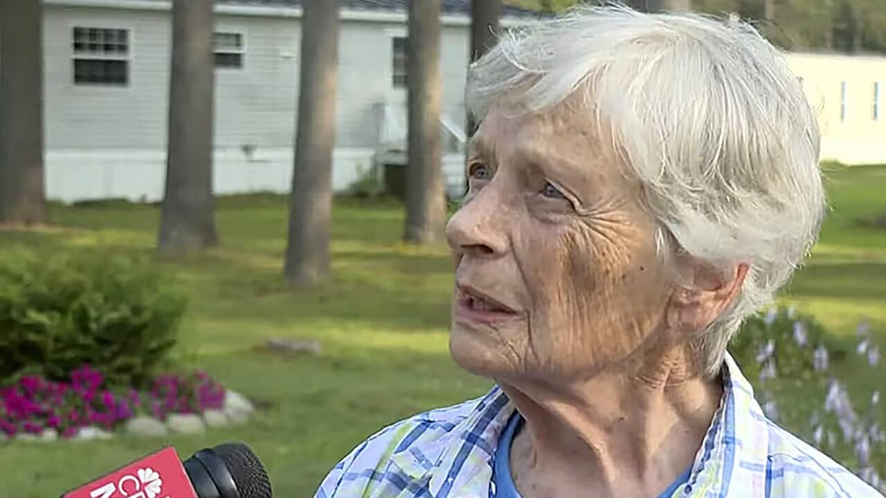 Marjorie Perkins standing in front of a house talking to a microphone from a local media.