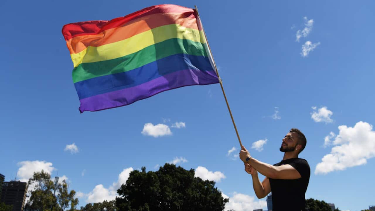 A man holds a rainbow flag