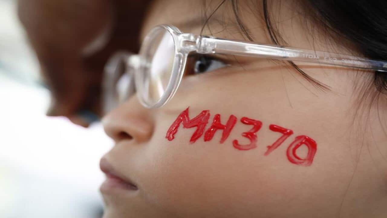 , a girl has her face painted during the Day of Remembrance for MH370