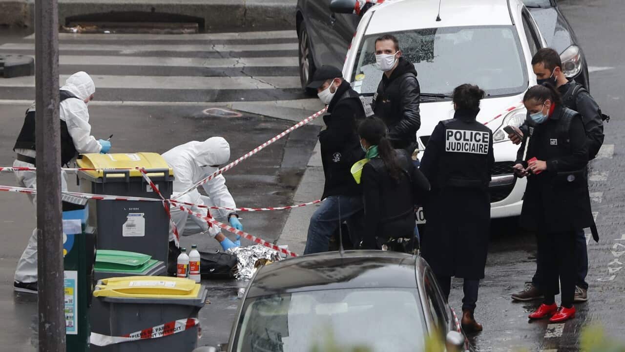 Police officers patrol the site of a knife attack near the former offices of satirical newspaper Charlie Hebdo.