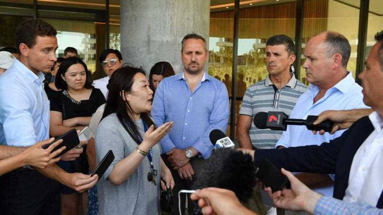 A resident (left) asks questions of Icon Managing Director Julian Doyle at a press conference outside the Opal Tower.