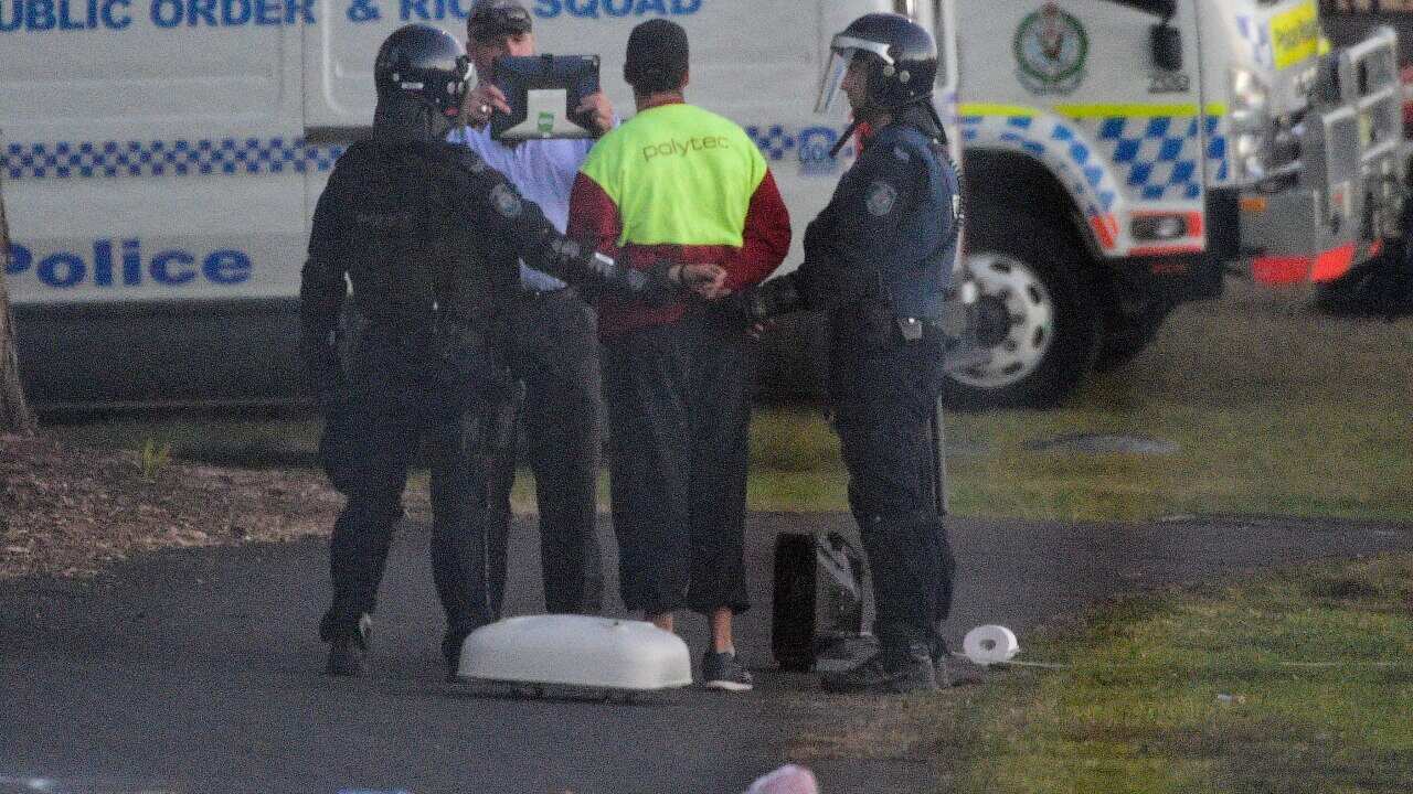 Riot police lead a detainee away in handcuffs during a riot at the Frank Baxter Juvenile Justice Centre.