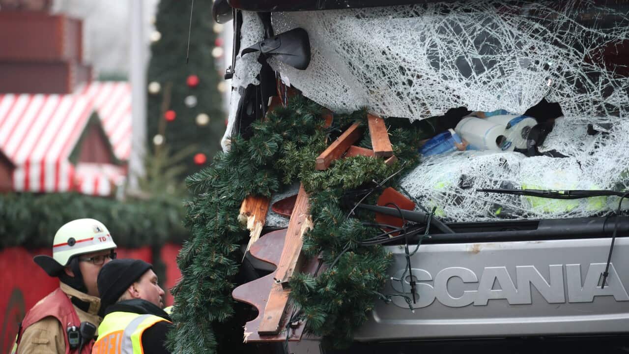 A police officer and fireman inspect a damaged truck on a road beside the Christmas market at Breitscheidplatz in Berlin, Germany, 20 December 2016.