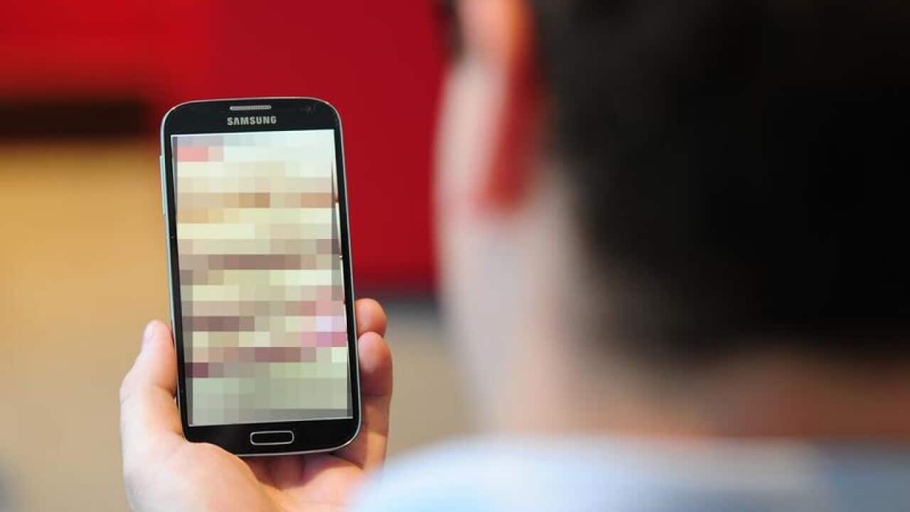 A posed picture of a man looking at a smartphone