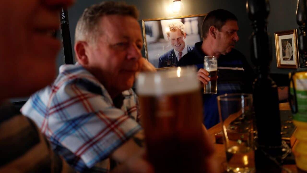 A portrait of Britain's Prince Harry hangs on the wall as drinkers at a bar inside a pub.