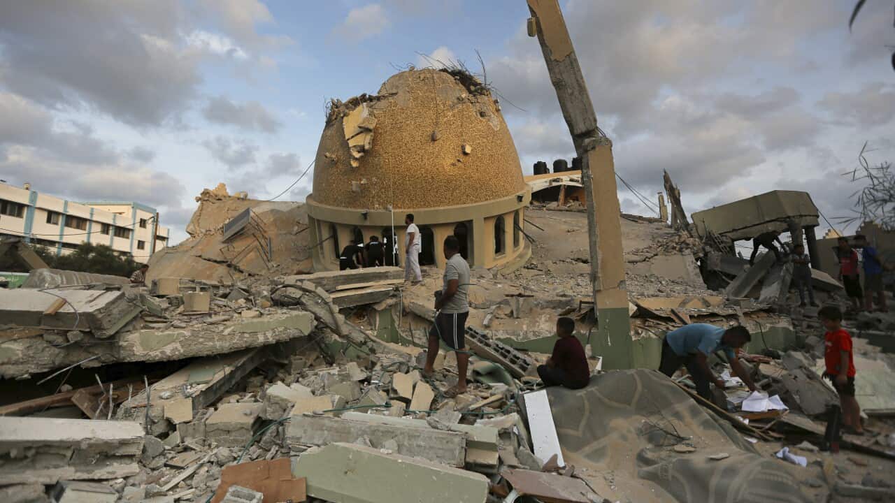 People stand outside a mosque destroyed in an Israeli air strike in Khan Younis, Gaza Strip, Sunday, Oct.8, 2023.