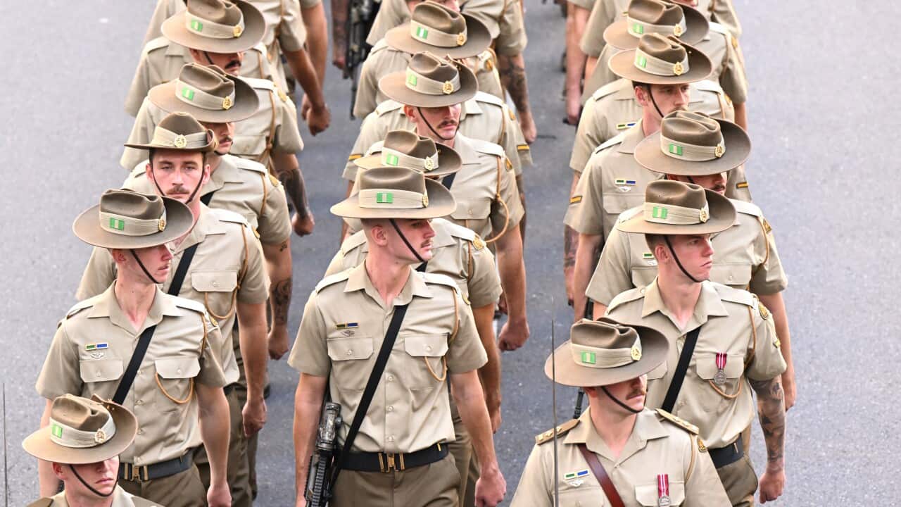 Young men dressed in ADF uniforms march down a street