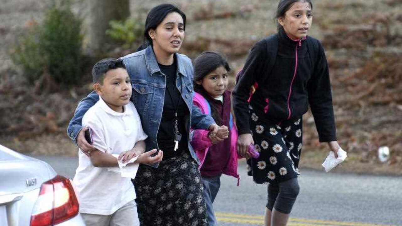 A woman escorts three children away from the scene of a fatal school bus wreck in Chattanooga, Tenn., Monday, Nov. 21, 2016.