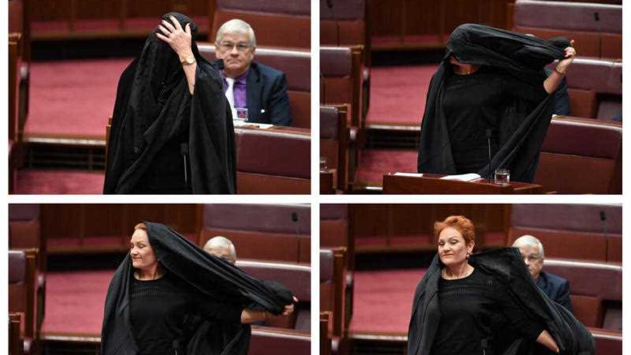 One Nation Senator Pauline Hanson takes off a burqa in the Senate.